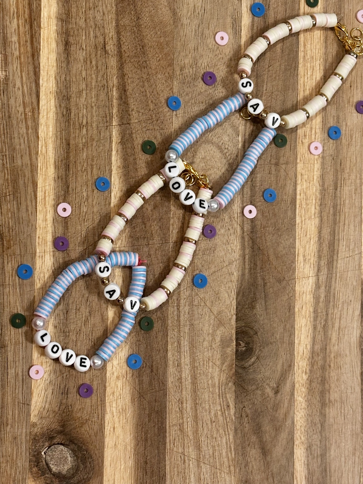 Flat lay of pastel S.A.V love bracelets